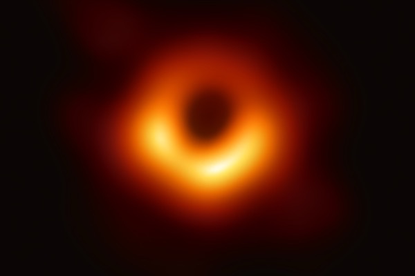 The first image of a black hole: a glowing orange ring of hot gas around a dark center, captured by the Event Horizon Telescope in 2019.